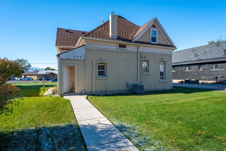Exterior stucco finish building featuring multiple windows, a concrete walkway, and a manicured lawn