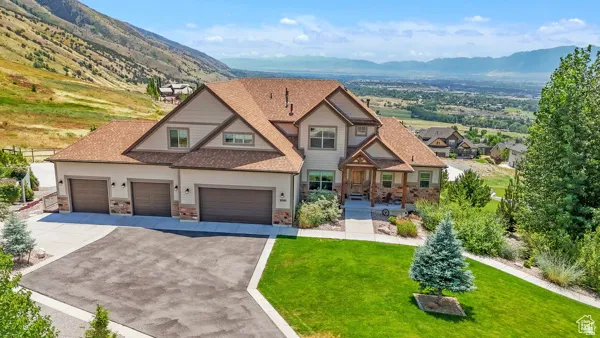 Multi-level residence featuring a prominent gabled roofline, a three-car garage, and a covered entry porch with stone and wood accents