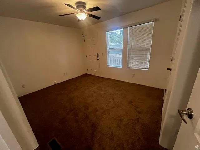 Spacious room featuring brown carpet flooring, light-toned walls, and a ceiling fan with integrated lighting