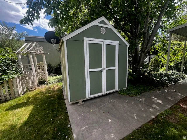 Green storage shed with white trim and double doors