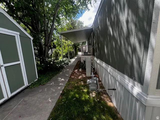 Exterior features a side walkway, an attached covered carport, and a detached storage shed