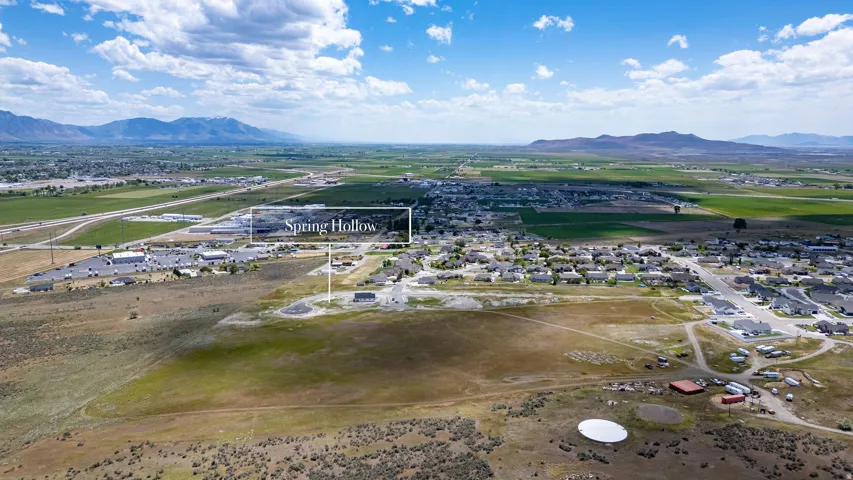 Aerial perspective showcasing a residential community with surrounding green fields and distant mountains