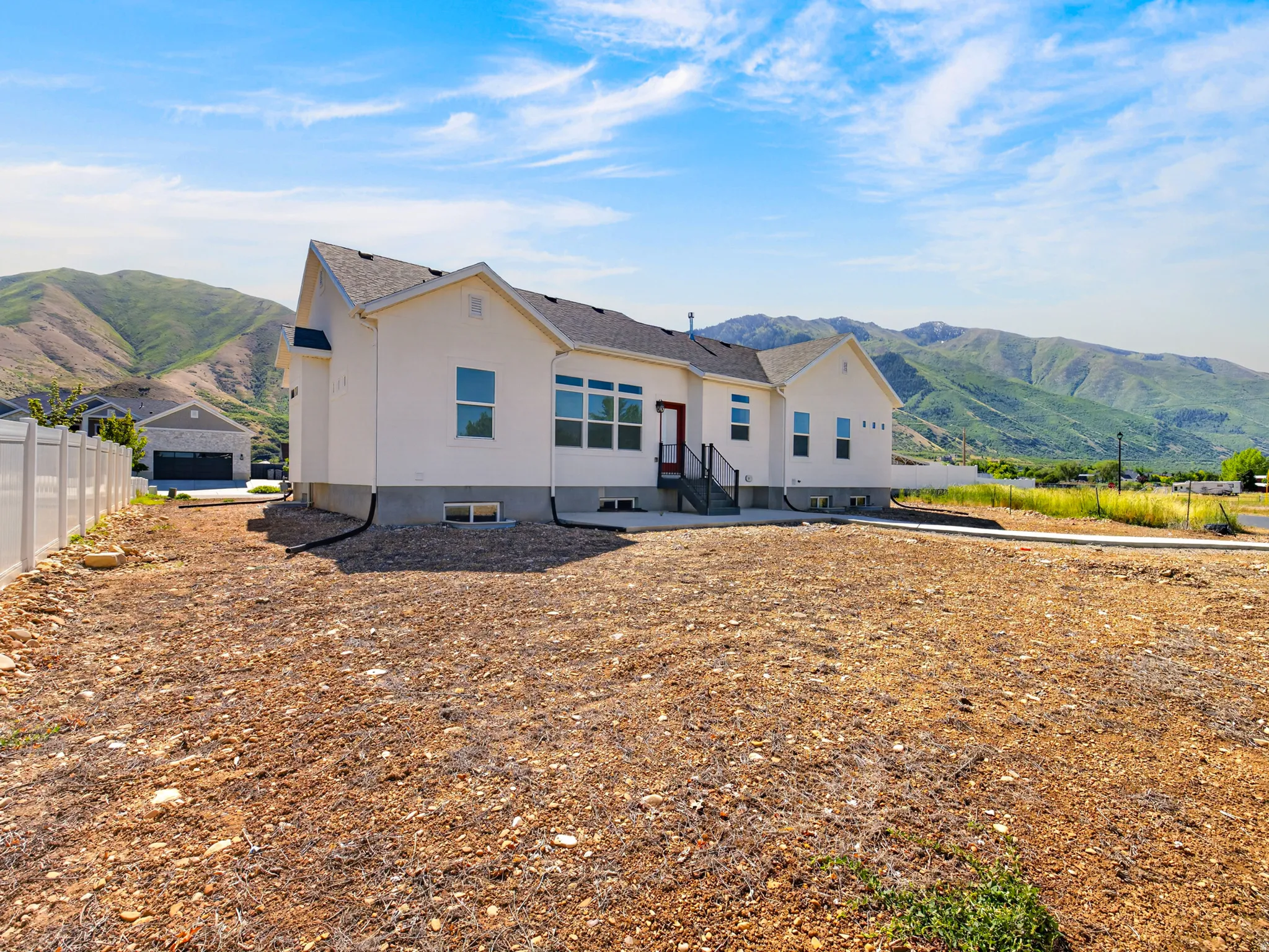 Modern ranch-style home featuring a white exterior, gray roof, and a vibrant red entry door