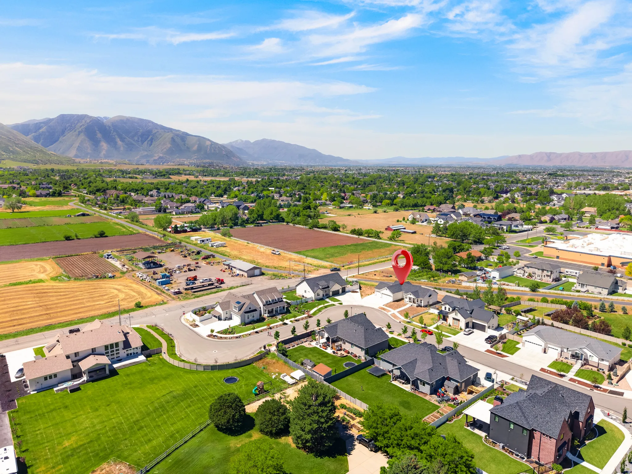 Aerial perspective of a developed residential area featuring various single-family homes with dark-pitched roofs and light-colored exteriors