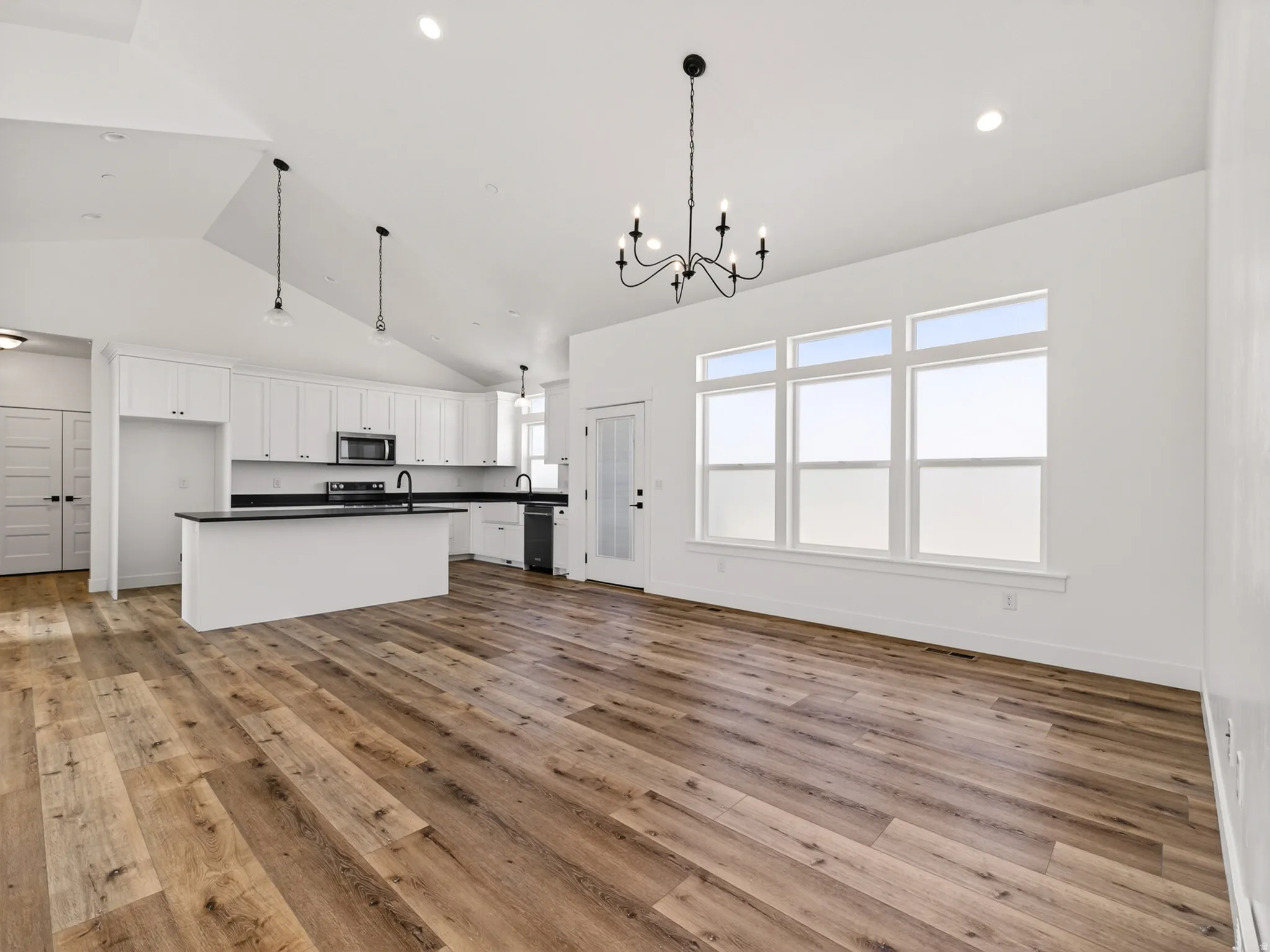 Open-concept living area featuring wood-finish flooring, vaulted ceilings, and recessed lighting