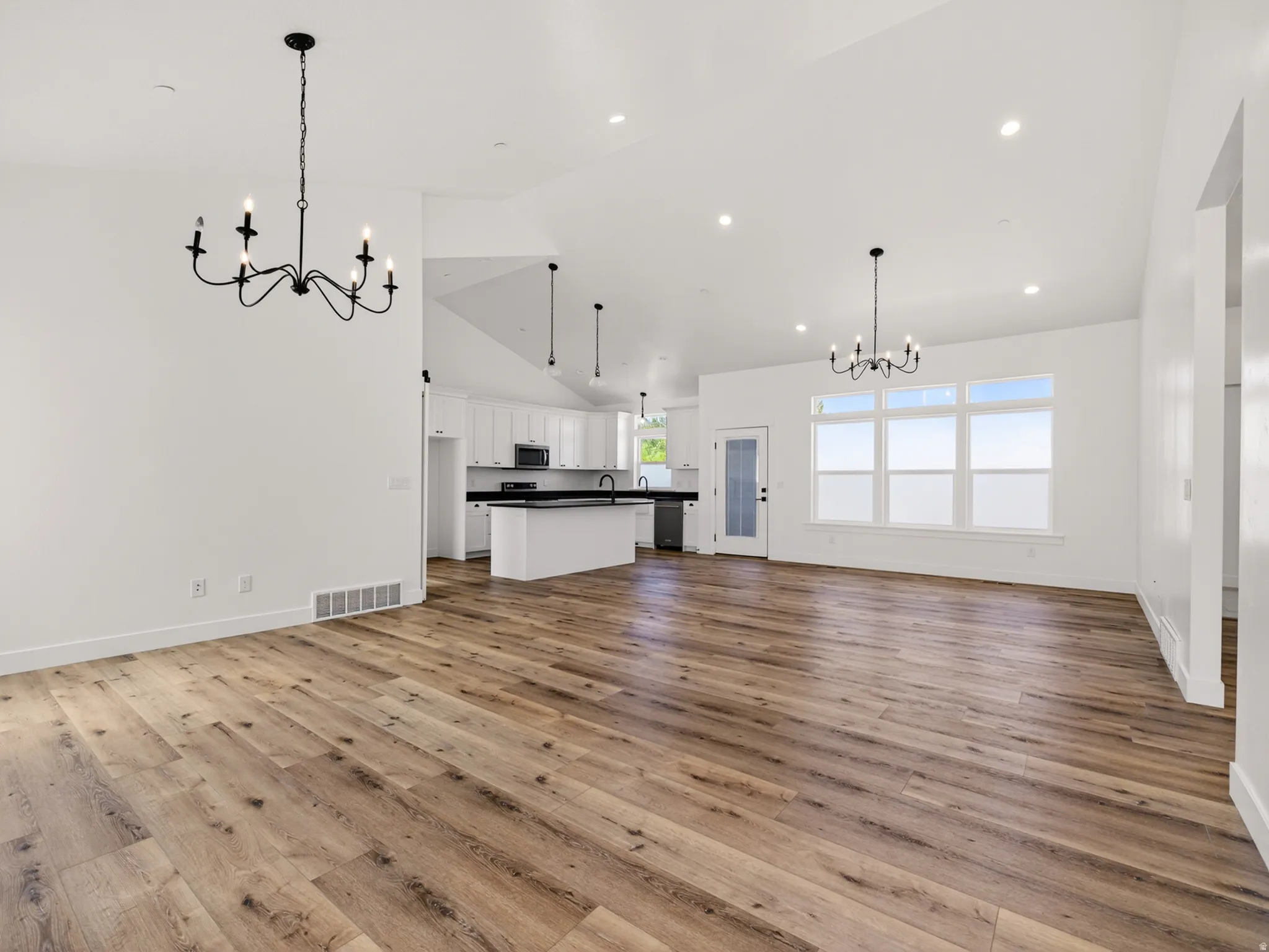 Open-concept living area featuring wood-finish flooring, vaulted ceilings, and recessed lighting