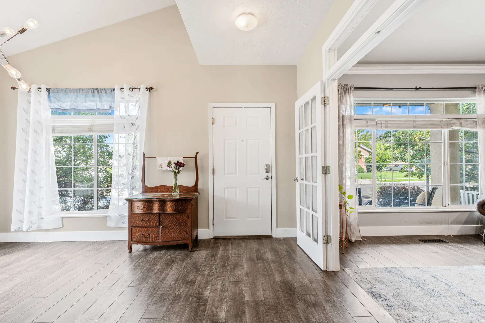 Vaulted ceiling with an attached light fixture, wood-finish flooring, and French doors