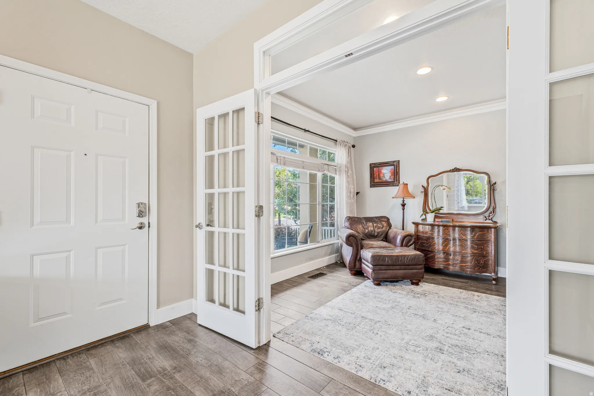 Entryway featuring wood-finish flooring, a paneled entry door, and French doors opening to an interior room with a large window