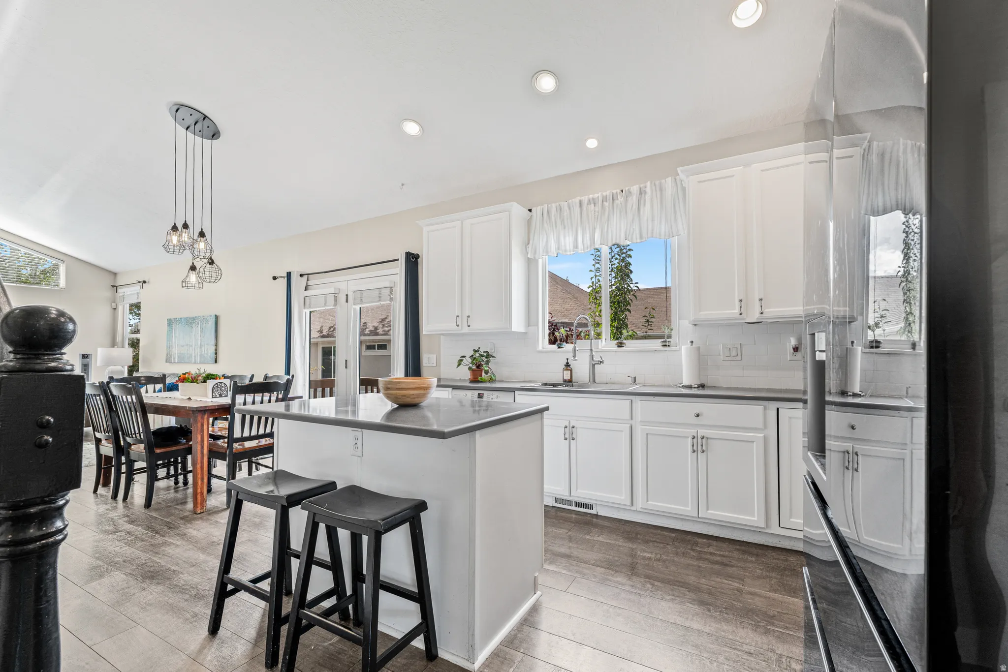 Kitchen with white cabinetry, gray countertops, wood-finish flooring, recessed lighting, and a kitchen island with seating