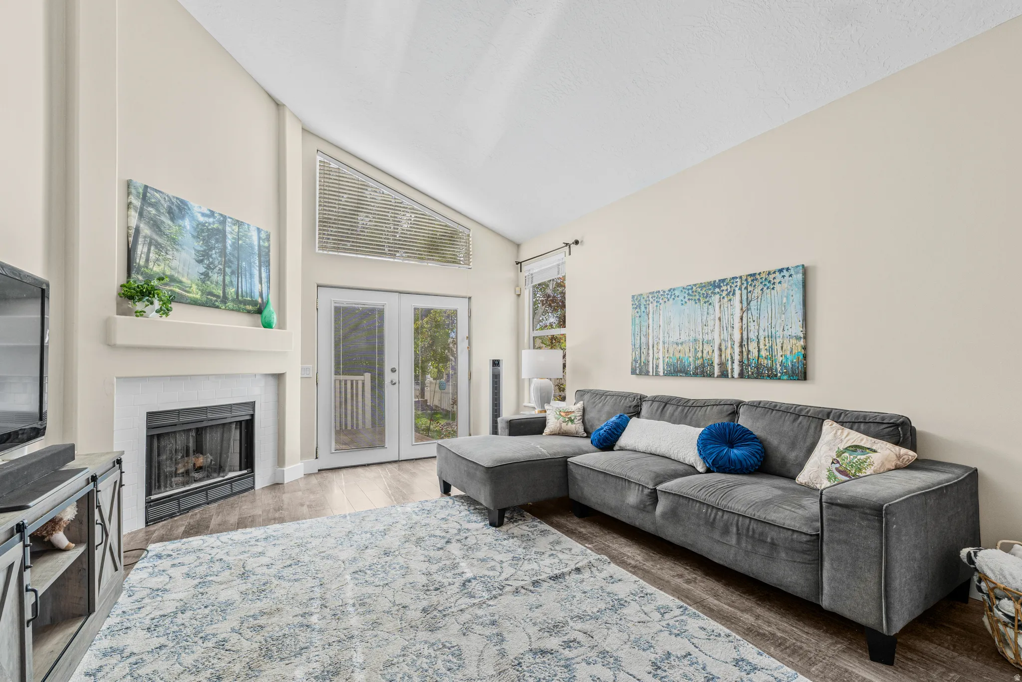 Vaulted ceilings, a built-in fireplace, wood-finish flooring, and double glass-paneled doors