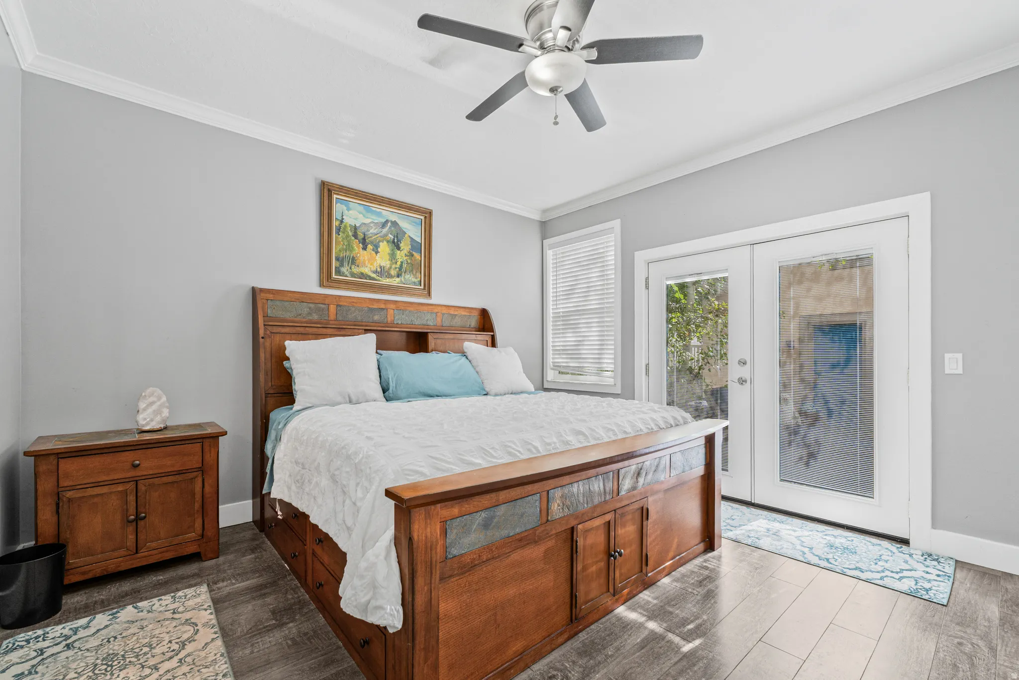 Wood-finish flooring, ceiling fan, white crown molding, white window blinds, and white French doors