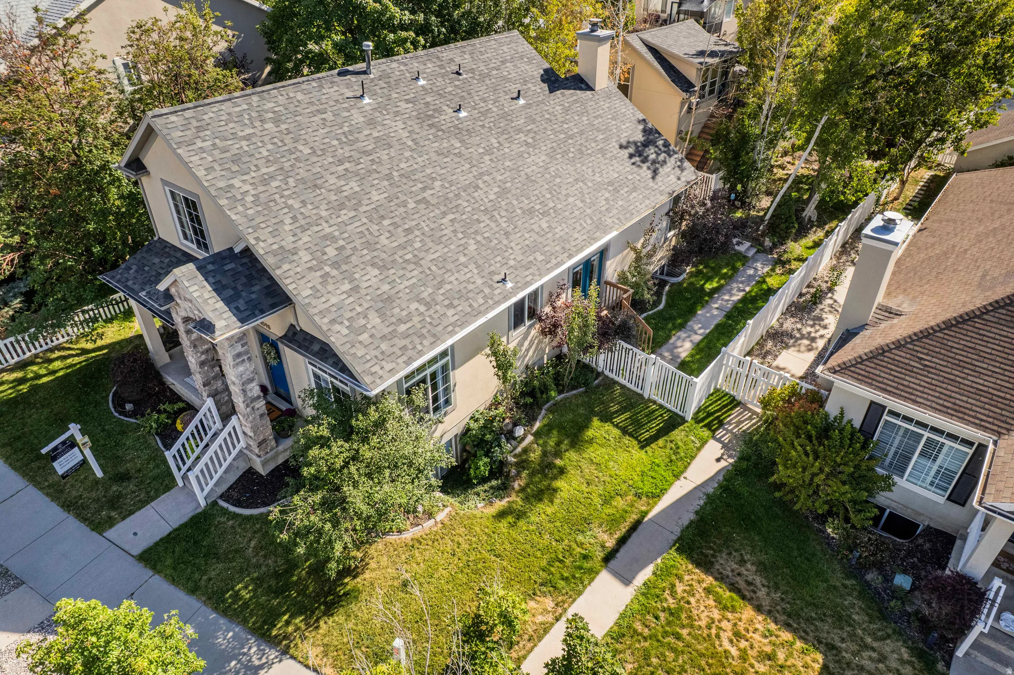 Two-story residence with a pitched shingle roof, stone and stucco exterior, and a covered front porch