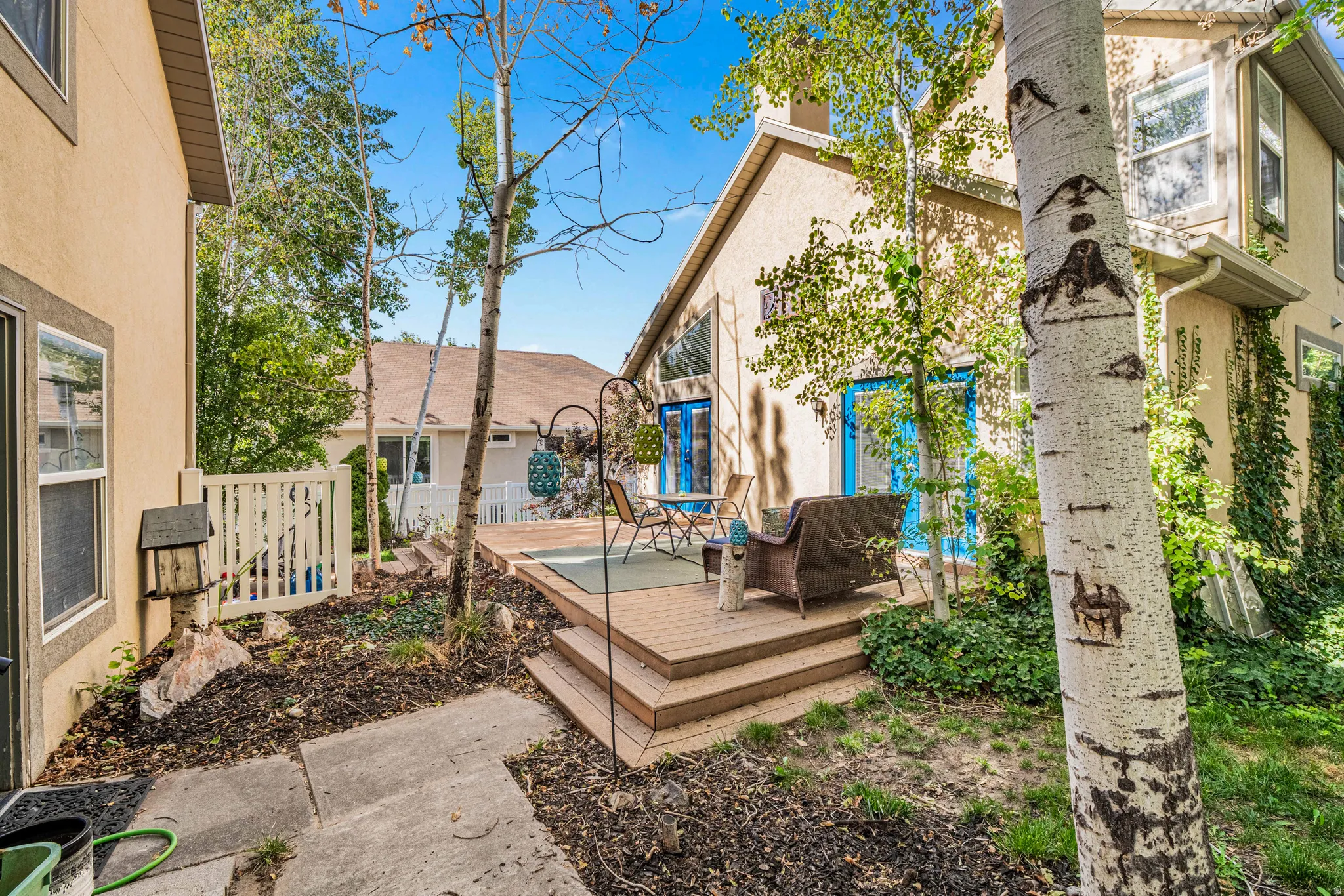 Outdoor wood-finish decking with stairs, bordered by mature trees and landscaping