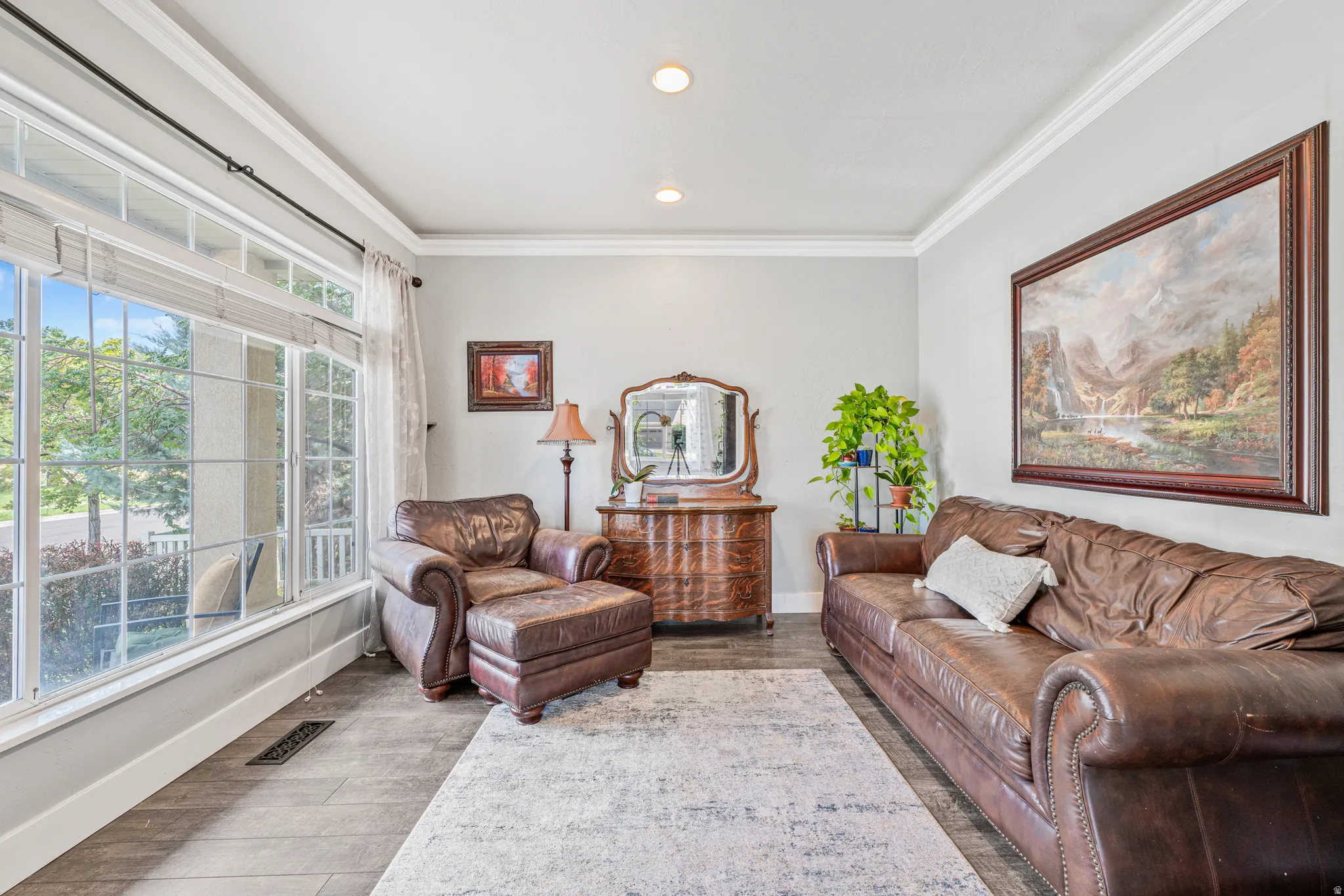 Large picture window, recessed lighting, crown molding, light gray wall color, wood-finish flooring