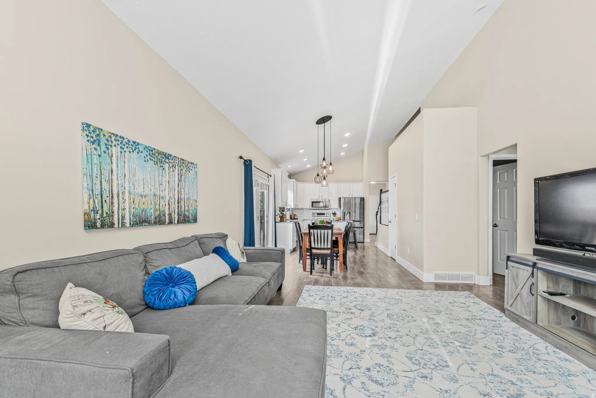 Vaulted ceiling with recessed lighting, wood-finish flooring, white baseboards, and a modern pendant light fixture