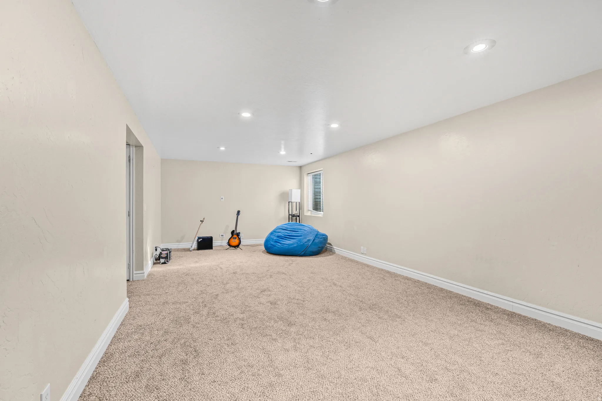 Recessed lighting illuminates the carpeted flooring and light-toned walls