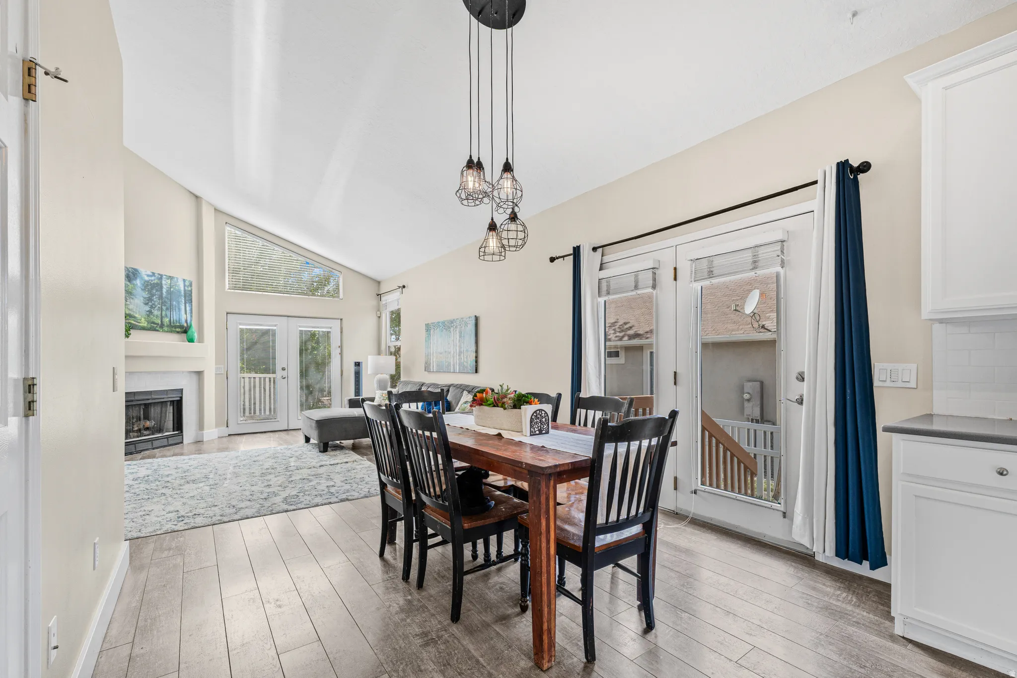 Vaulted ceiling with skylight, fireplace with mantel, French doors, wood-finish flooring, and pendant lighting