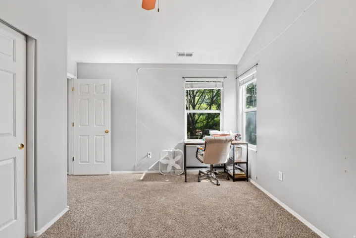Carpeted flooring, white paneled doors, and multiple windows
