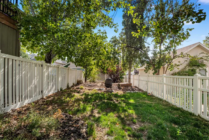 Fenced yard with mature trees and a sloped landscape