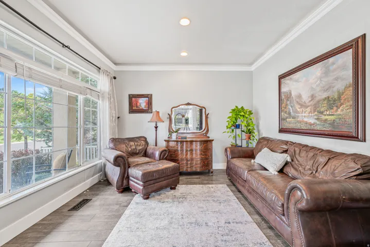 Large picture window, recessed lighting, crown molding, light gray wall color, wood-finish flooring