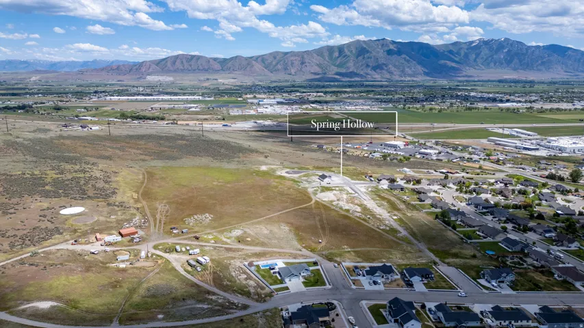 Aerial perspective of developing residential area with established homes, new construction, and undeveloped land
