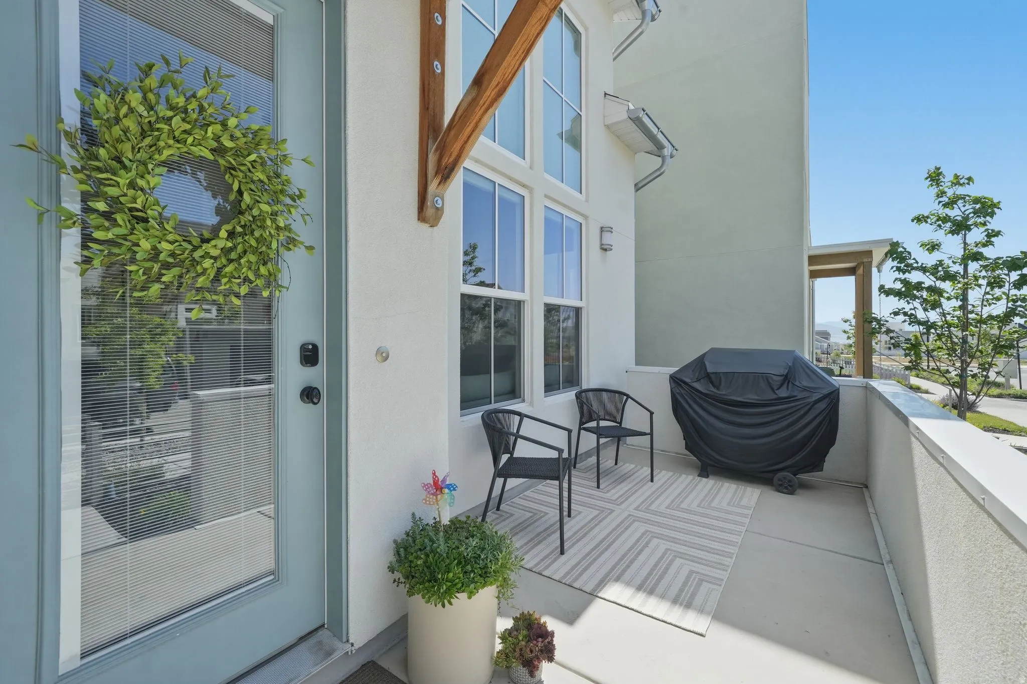Private balcony featuring a stucco exterior, contemporary lighting fixtures, and a glass-paneled entry door