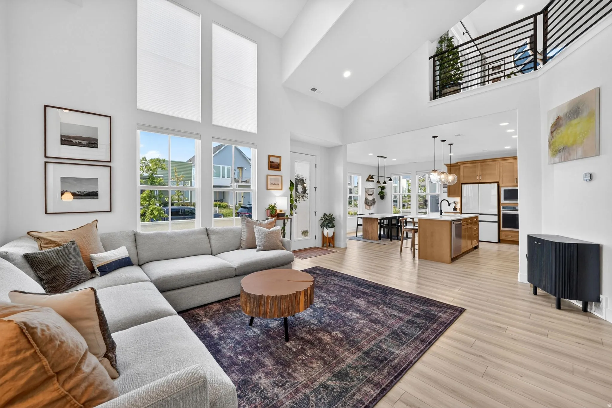 Spacious open-concept living area featuring a vaulted ceiling and an upper-level balcony with metal railing