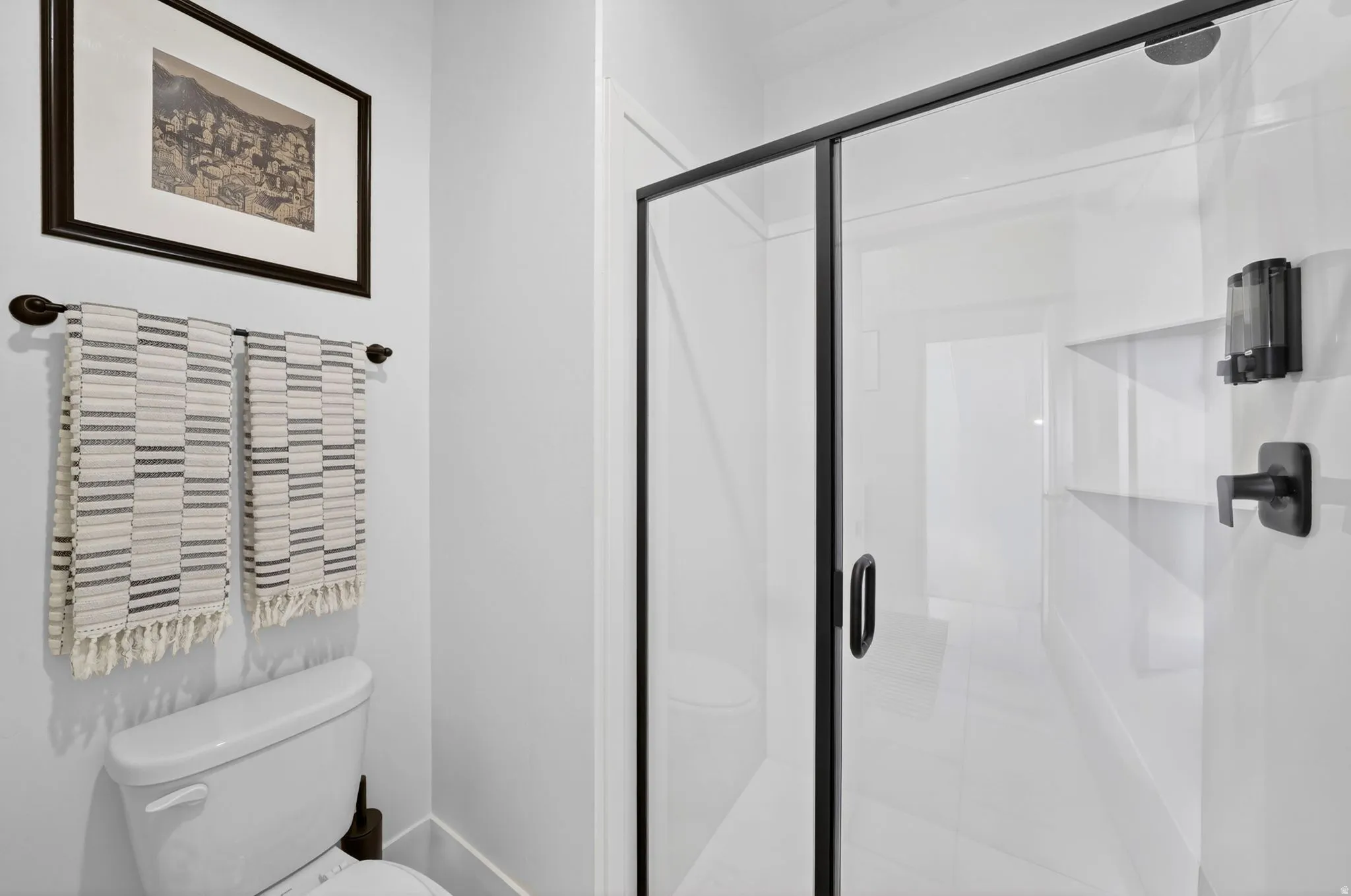 White-tiled shower with a clear glass enclosure and matte black fixtures
