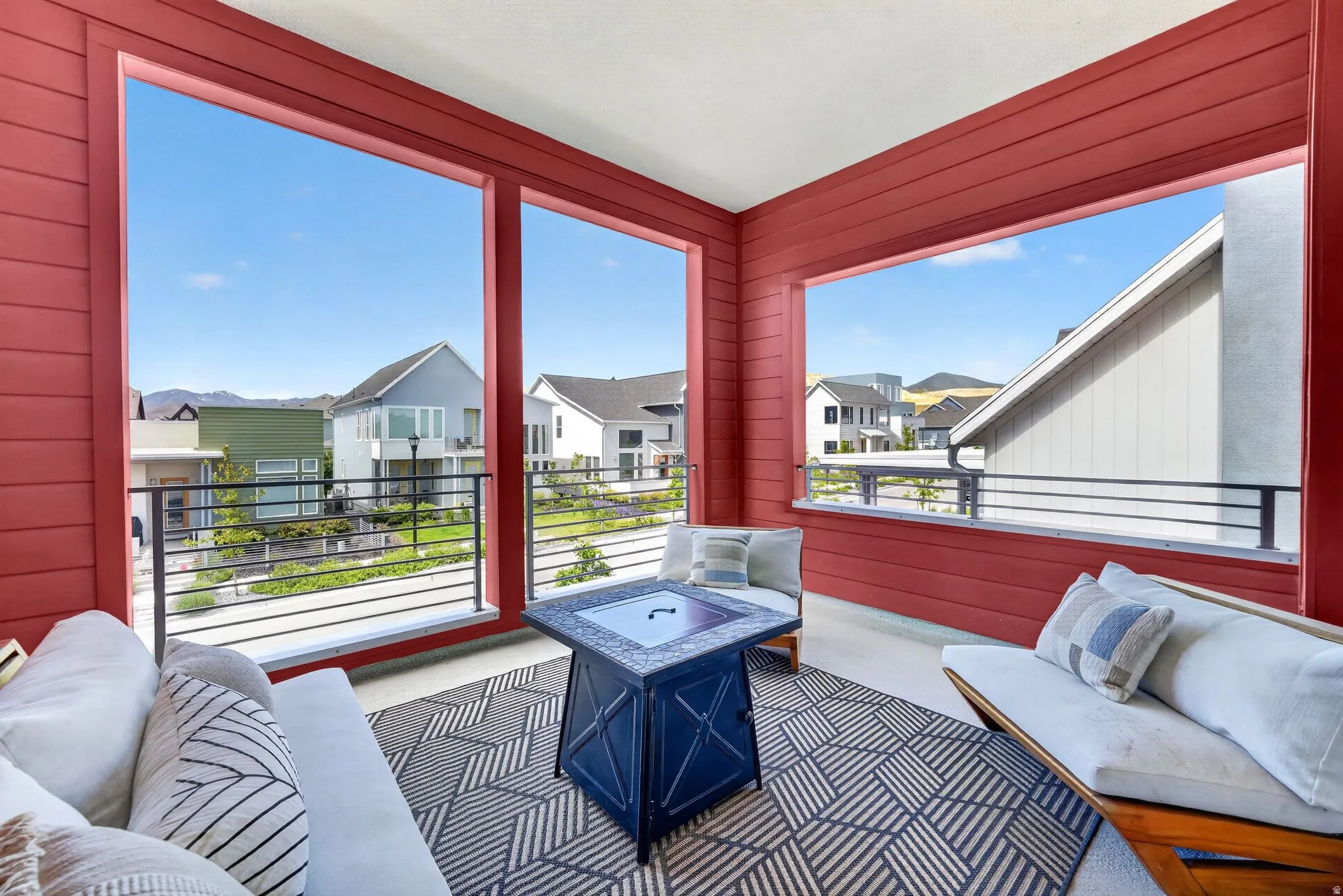 Covered outdoor patio featuring extensive red horizontal siding, concrete flooring, and an open railing system