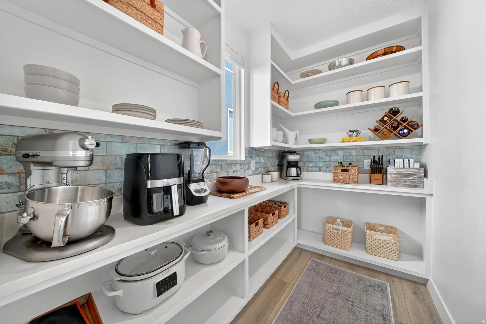 Spacious walk-in pantry featuring extensive built-in shelving, white countertops, and a full-height tile backsplash