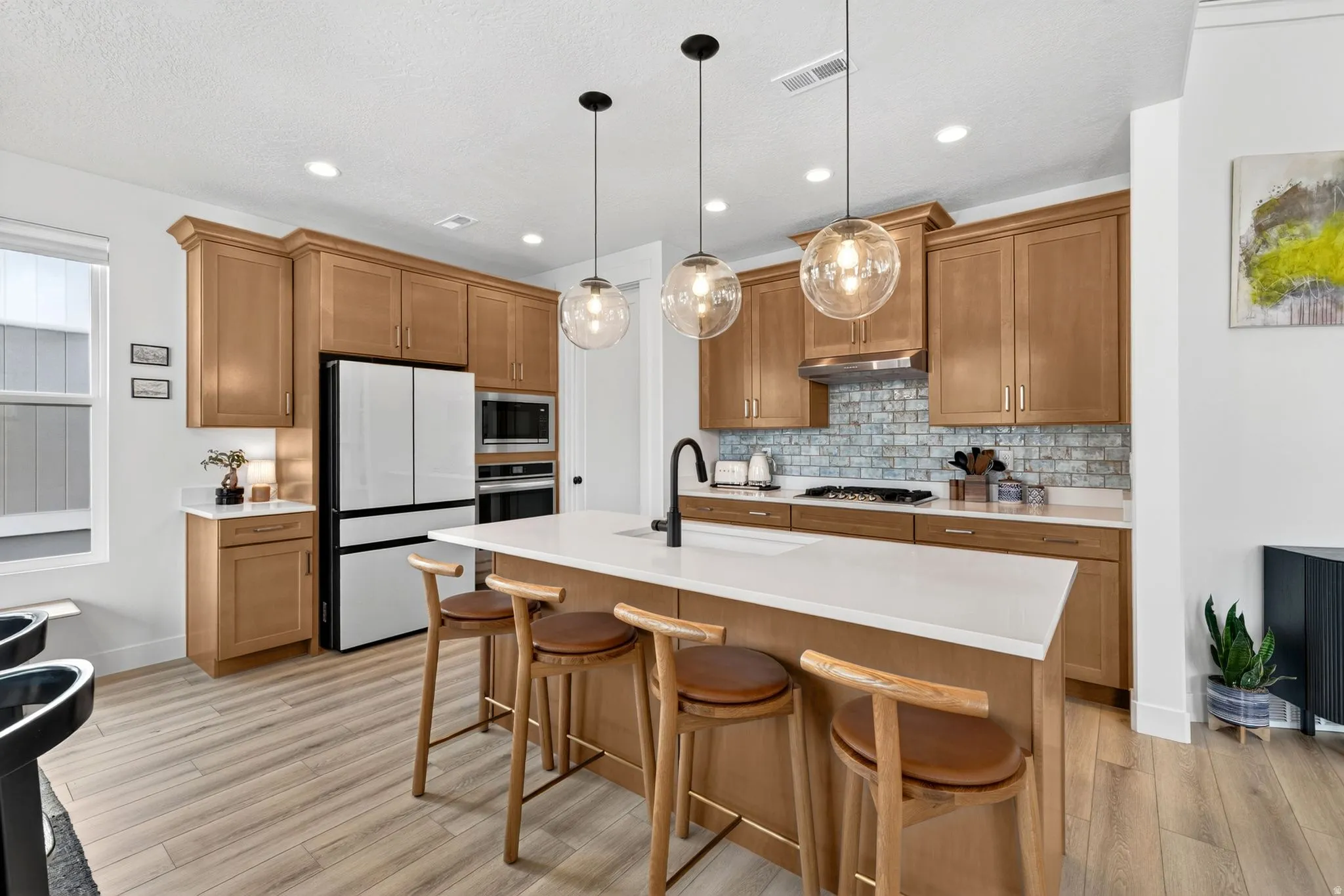 Contemporary kitchen featuring light wood-finish cabinetry, white countertops, and wood-finish flooring