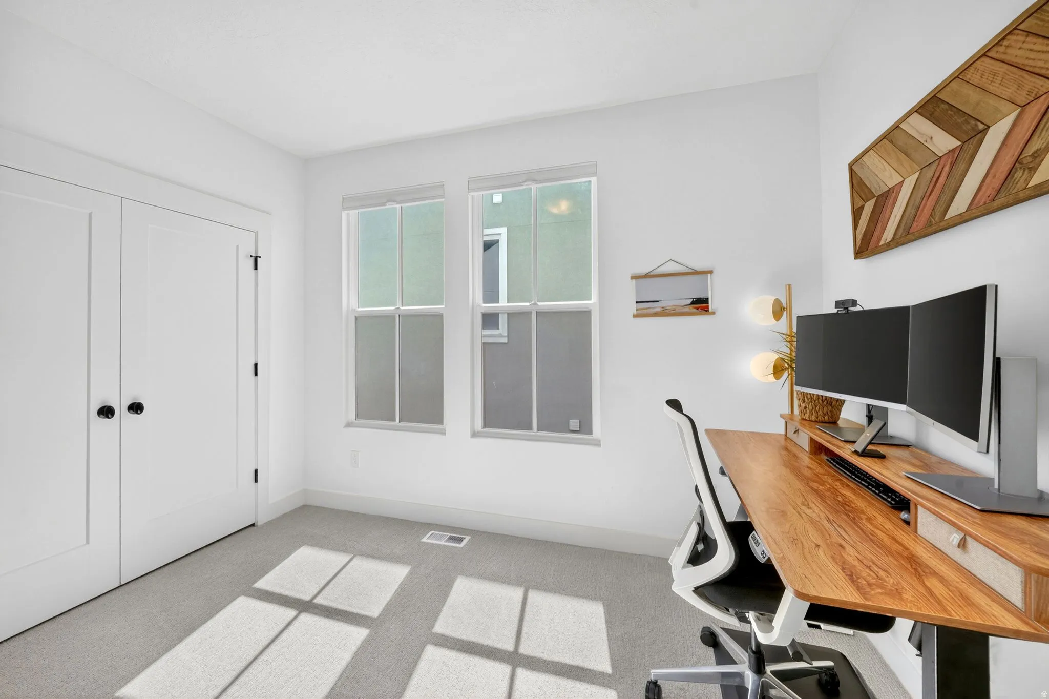 White walls showcasing a light grey carpet, dual white paneled doors with black hardware, and two large double-hung windows