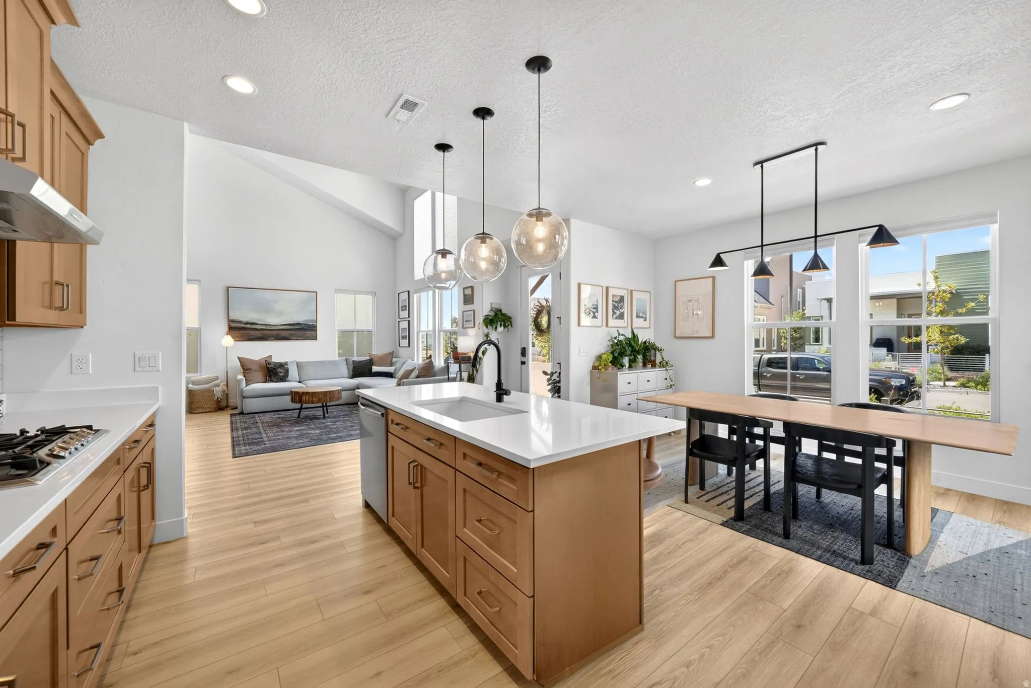 Open-concept living space featuring wood-finish flooring, a kitchen island with a white countertop, light wood cabinetry, and recessed lighting