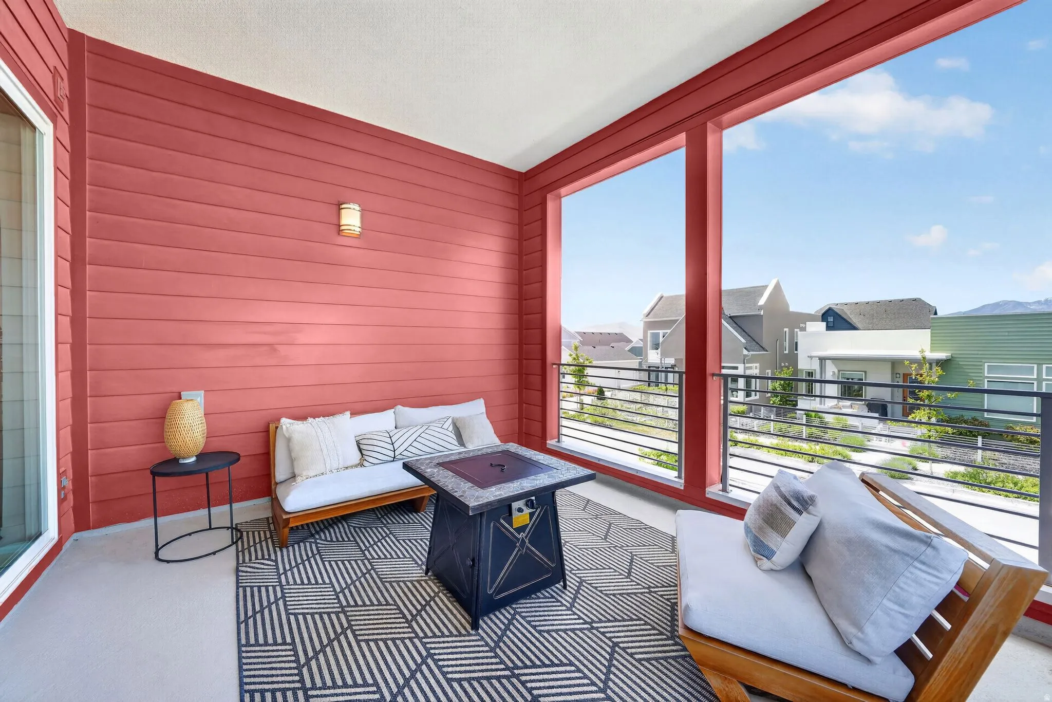 Covered balcony featuring red horizontal siding, concrete flooring, and a metal railing