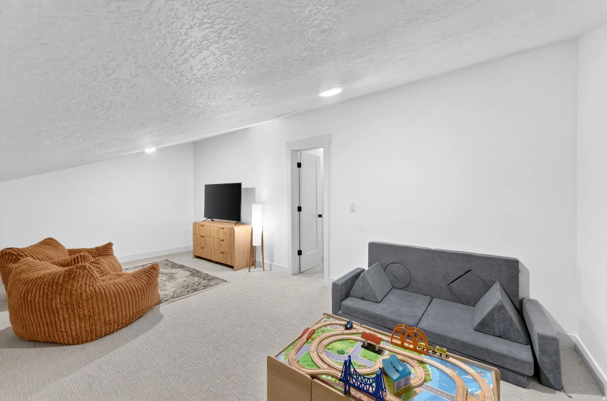 Carpeted room with a textured ceiling, recessed lighting, and white walls