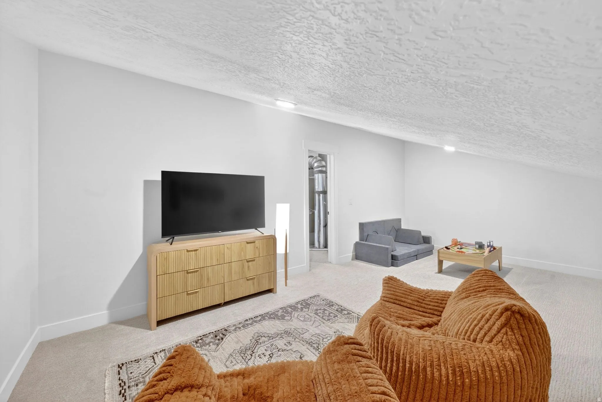 Spacious bonus room featuring an angled ceiling, light-toned carpeting, and white wall finishes