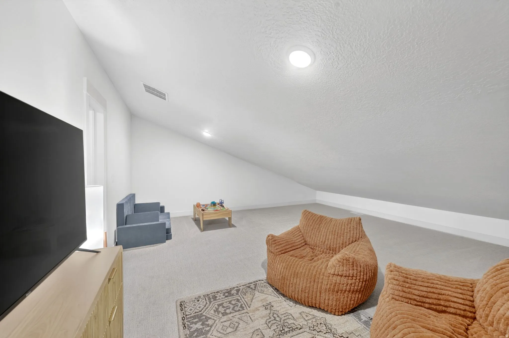 Carpeted room with a sloped ceiling and recessed lighting