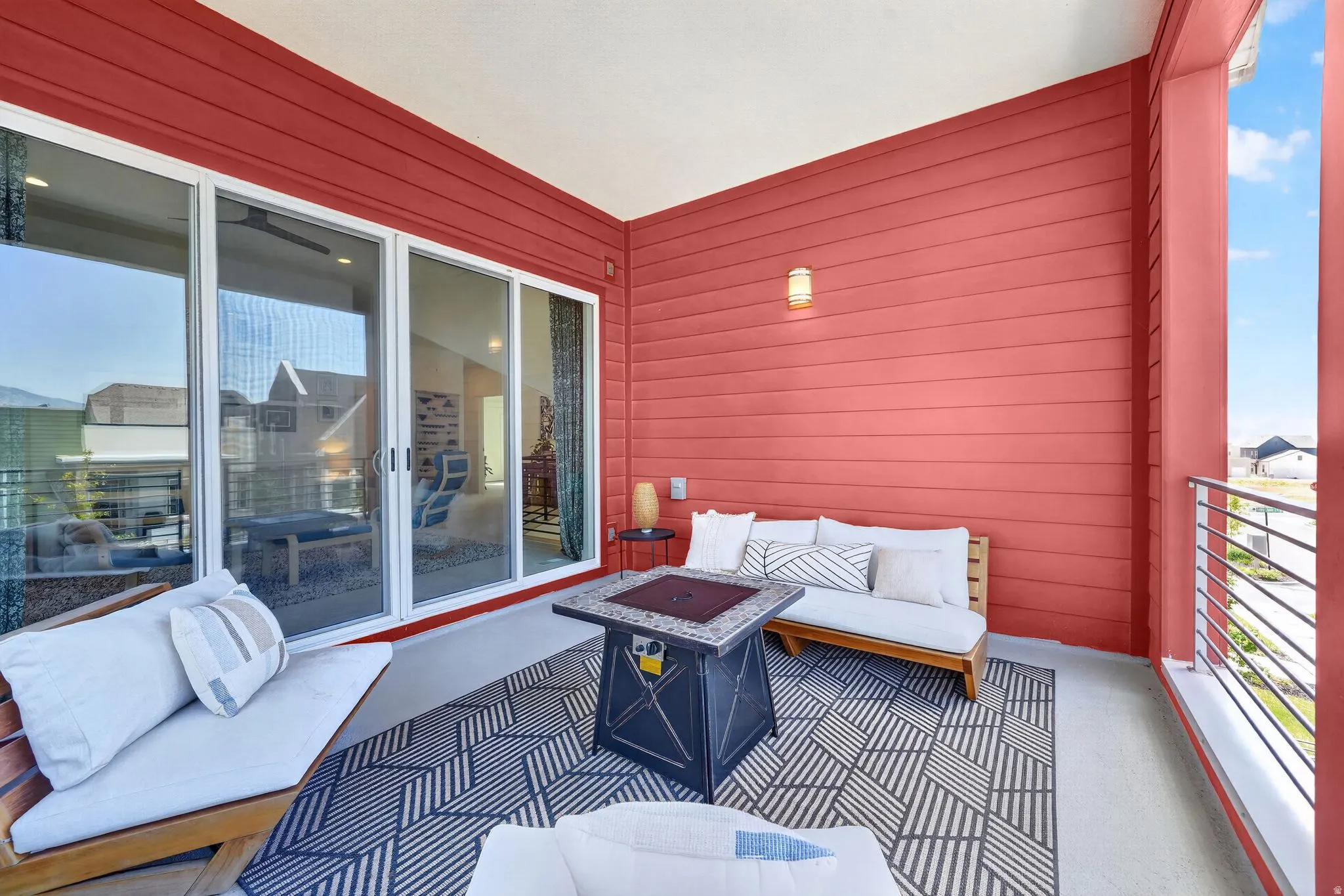 Covered outdoor patio featuring extensive sliding glass doors, a modern wall-mounted light fixture, and horizontal siding