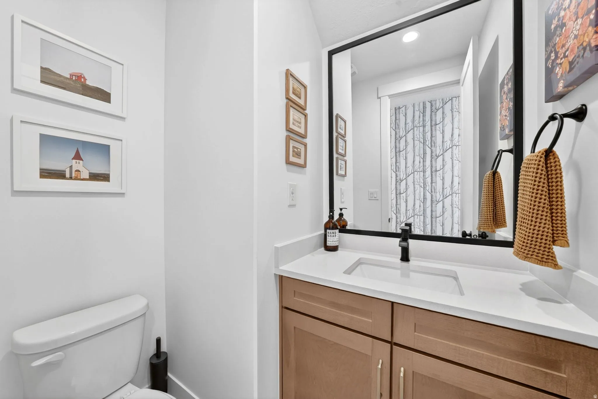 Bathroom featuring a framed mirror, a countertop with an integrated sink, a dark-finish faucet, and wood-finish cabinetry