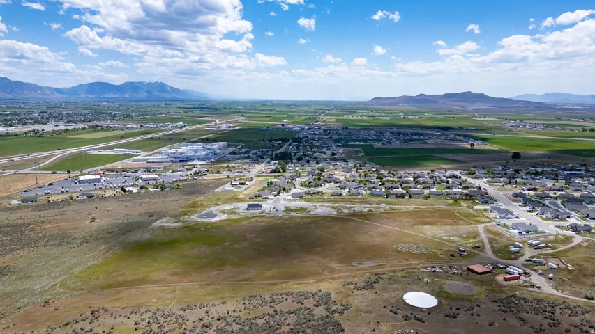 Expansive aerial panorama showcasing a rural landscape with distant mountains, open fields, and scattered residential areas