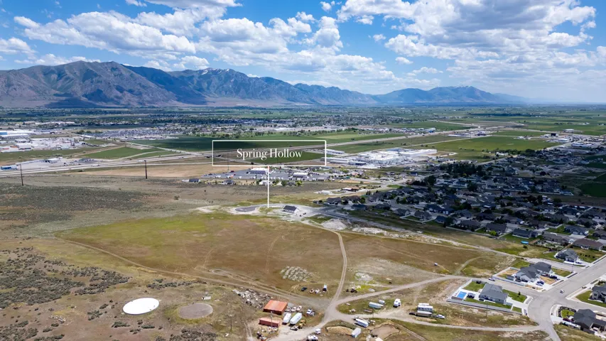 Expansive aerial capture showcasing a developing residential area with new construction and established homes, framed by a distant mountain range