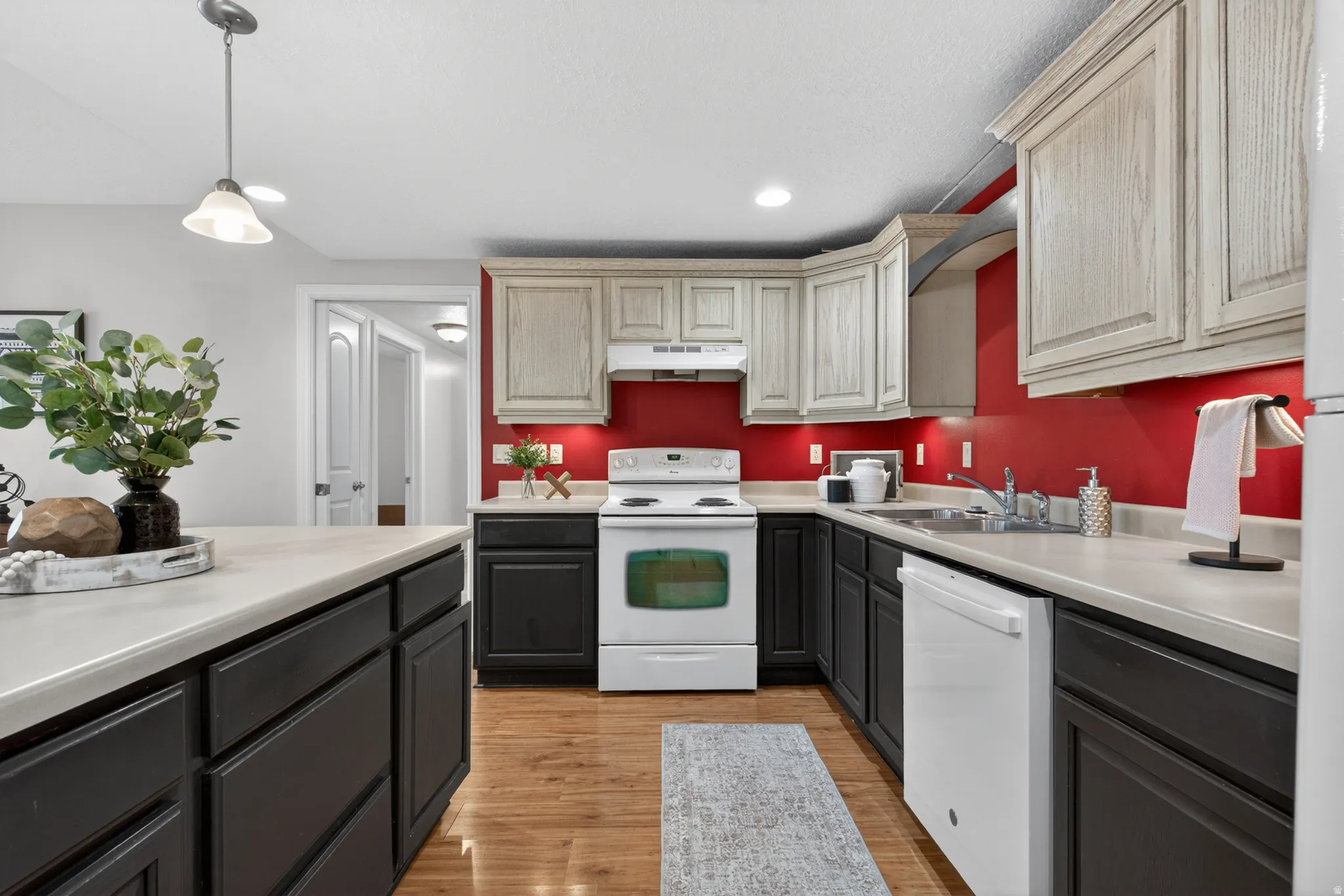 Kitchen featuring two-tone cabinetry with light upper and dark lower units, a white range, and a white dishwasher