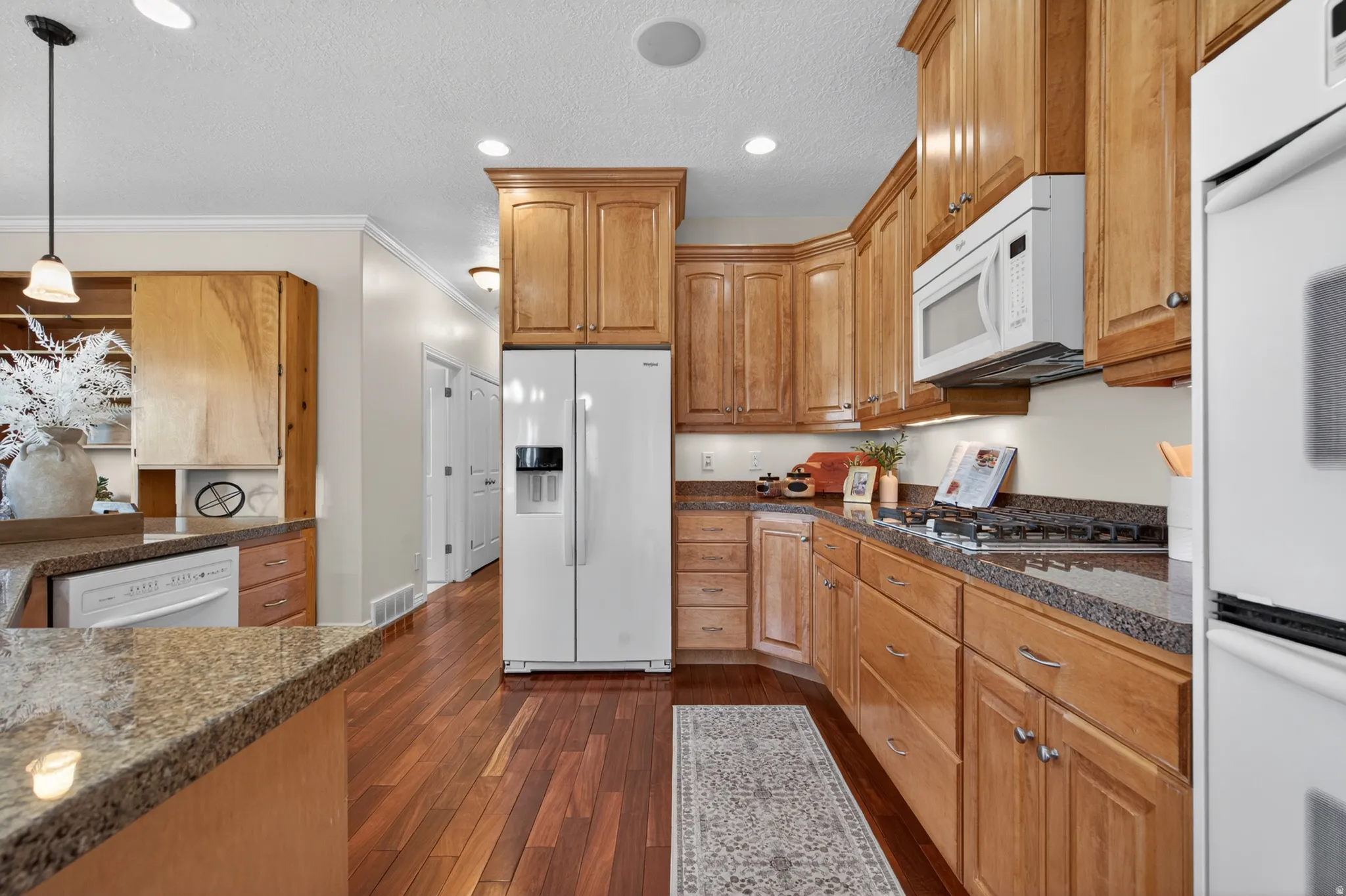 Kitchen featuring wood-finish cabinetry, granite-style countertops, wood-finish flooring, recessed lighting, and a built-in microwave