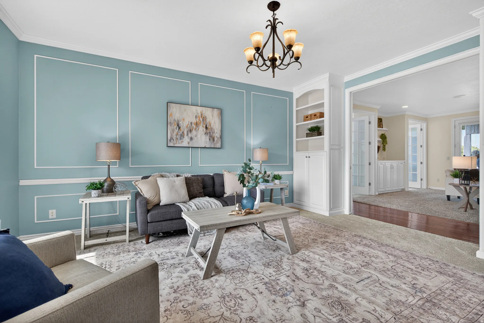 Living space featuring wall molding accents, a built-in cabinet with shelving, and a decorative chandelier
