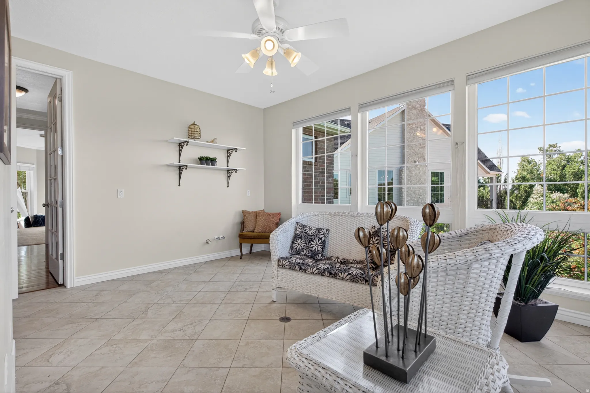 Sunroom featuring large grid-pattern windows with exterior views, tile flooring, and a ceiling fan with integrated lighting
