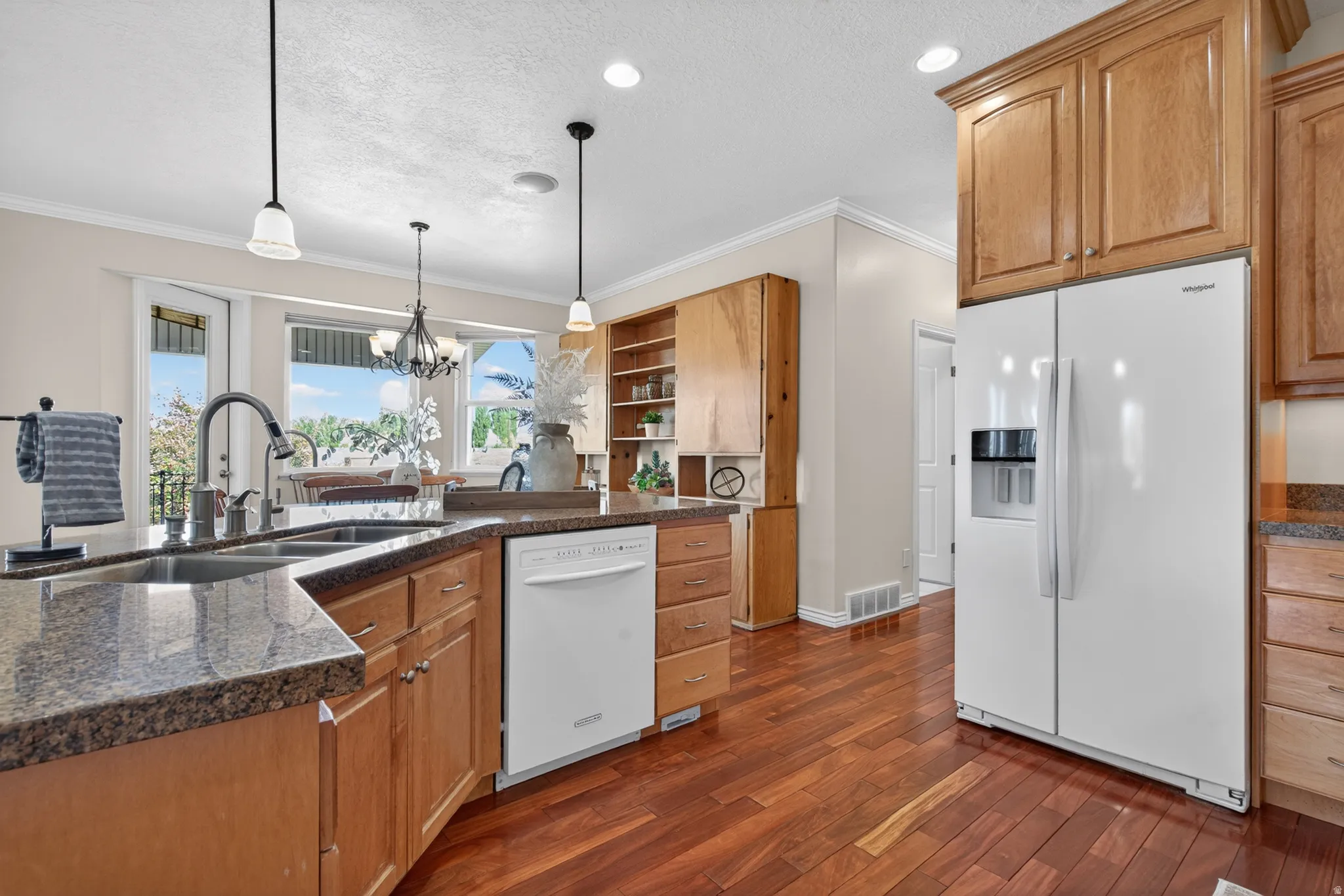 Kitchen featuring wood-finish flooring, granite-style countertops, wood cabinetry, stainless steel sink, and a white side-by-side refrigerator
