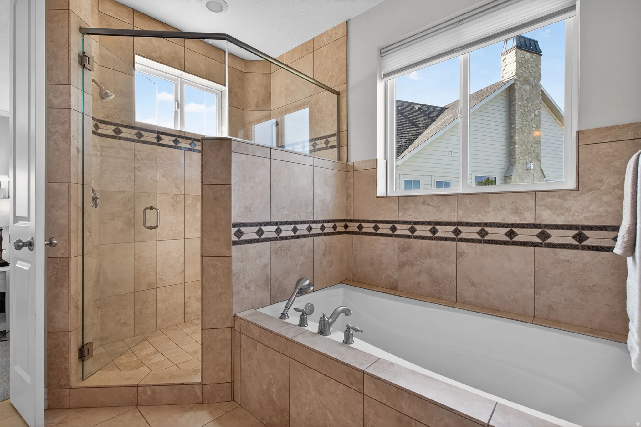 Tiled shower enclosure with a glass door, accompanied by a built-in soaking tub