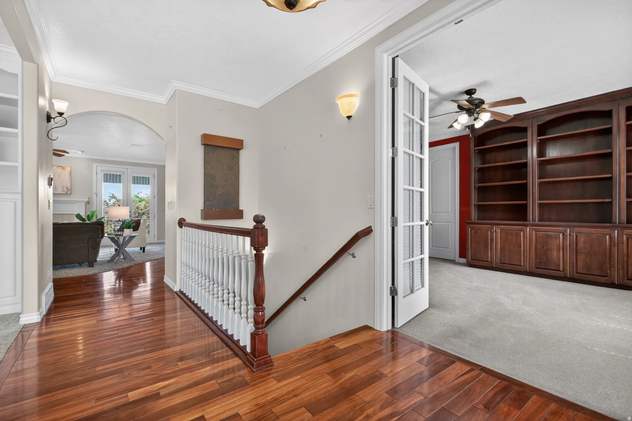 Cherry wood-finish flooring extends through the hallway, complemented by crown molding and a built-in bookshelf