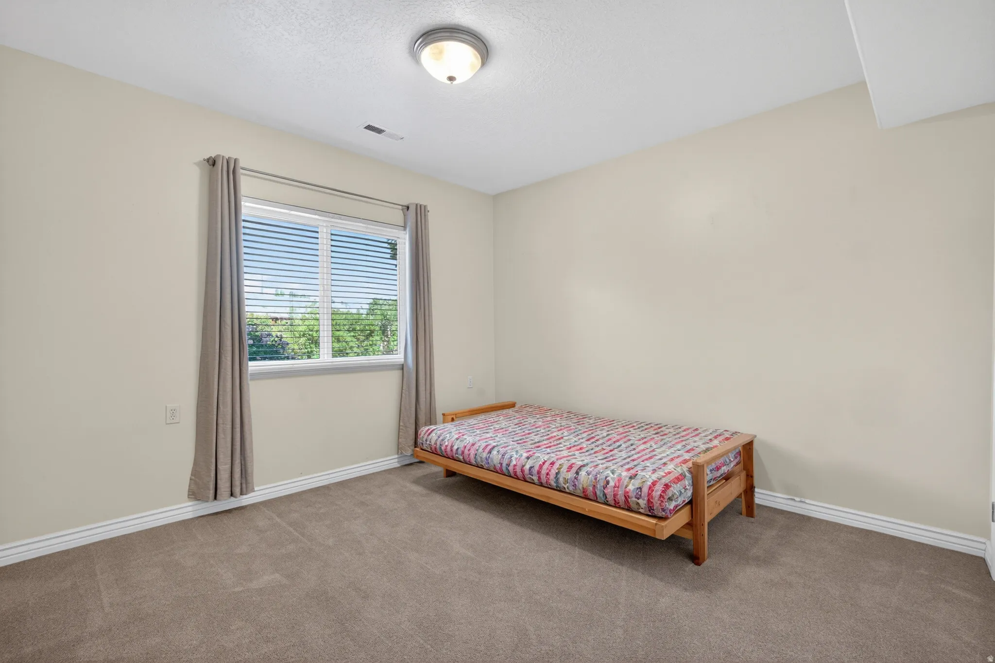 Carpeted room featuring a double window with horizontal blinds, neutral wall tones, and white baseboards