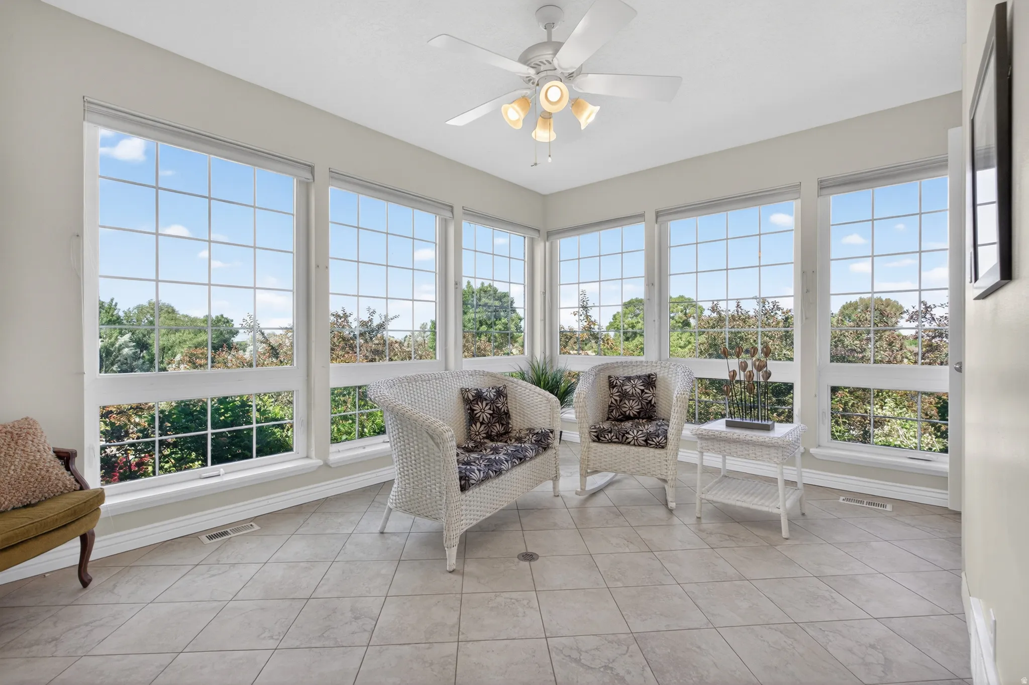 Sunroom featuring extensive window-paneled walls, a ceiling fan with integrated lighting, and tile flooring